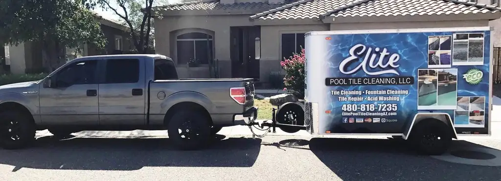 A white pickup towing the custom Elite Pool Tile Cleaning, LLC equipment trailer, lettered with the company name and phone number
